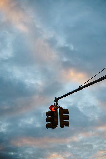 Traffic light in NYC against the cloudy sky.