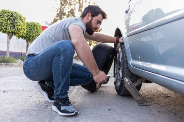 istock young man lifting a car with a car jack to change a tire 1463965904