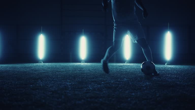 talented junior football player training alone in night, closeup view of legs, freestyle dribbling