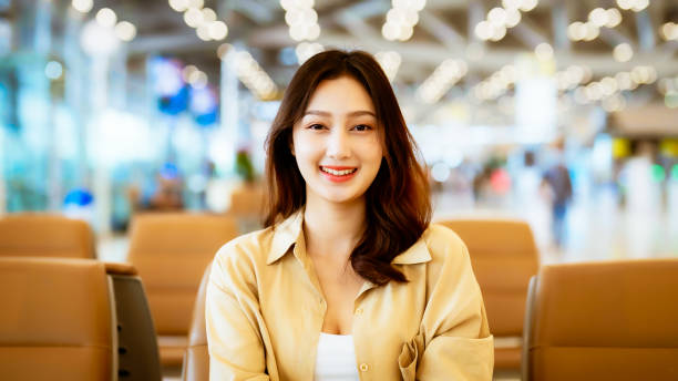 Asian woman waiting for departure at the airport on vacation holiday. Portrait smiling asian young woman looking to camera. Facial expression happy stock photo