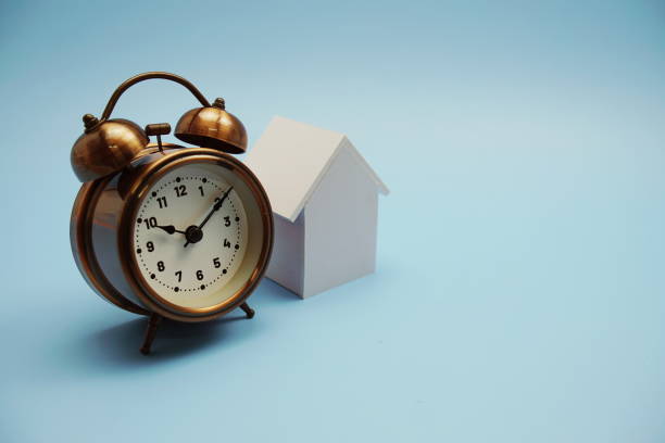 istock Alarm clock and house model with space copy on blue background 1463984314