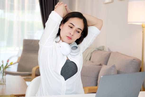 istock Young asian woman stretching body for relaxing while working with laptop computer at her desk, home office lifestyle 1463987526
