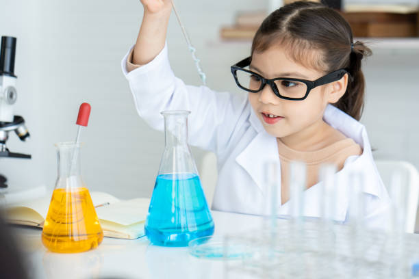 istock Asian girl, small, sitting in science room, studying in science class, practical class, He was squeezing water from flask, into beaker, Slowly, conduct experiment, and wait see results experiment. 1463988977