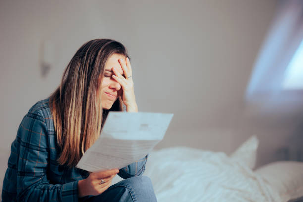 Unhappy Woman Reading a Document at Home stock photo