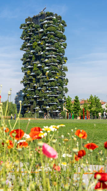 Milano, Italy. Bosco Verticale, view at the modern and ecological skyscraper with many trees on each balcony. Public park in the foreground with fresh and colored flowers