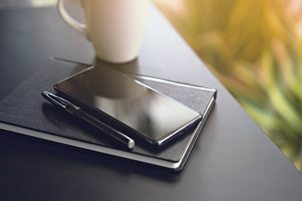 istock Close up smartphone and note book on black desk 1463999273