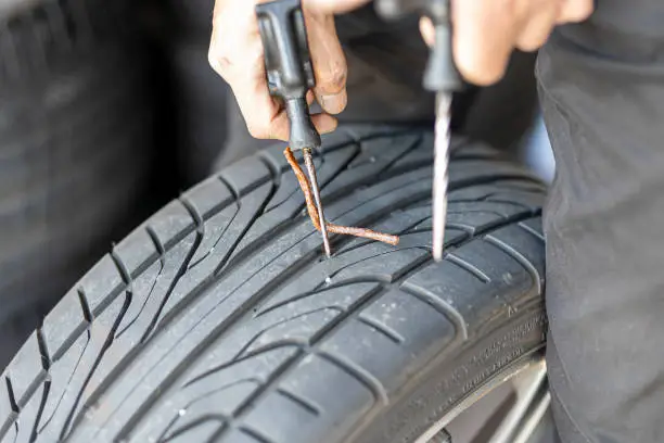 Photo of Mechanic repairing a flat tire in an auto body shop.