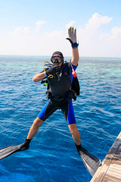 istock Middle aged Athletes  handsome men scuba divers ready for scuba diving,  jumping in   Beautiful tropical blue sea, coral reef  in the background. Water sports. 1464016269