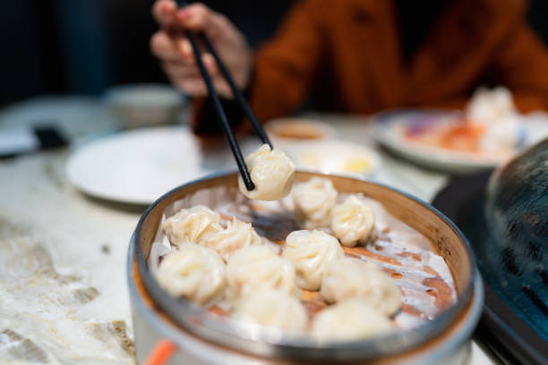 Lady picks up a xiao long bao with chopsticks