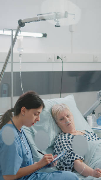 istock Medical assistant doing checkup visit for patient in hospital ward bed 1464017700
