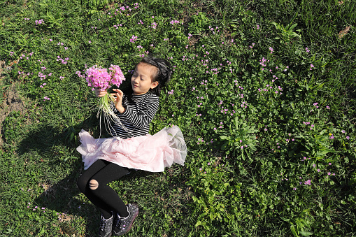 a asian girl picking and holding flowers on the meadow