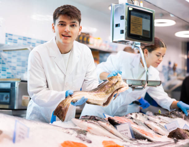 istock Positive salesman demonstrating cod in fish store 1464022790