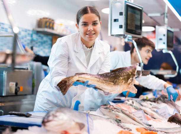 istock Positive saleswoman holding cod fish in fish store 1464022801