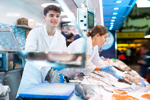 Portrait of salesman offering fresh fish atlantic cod at seafood shop