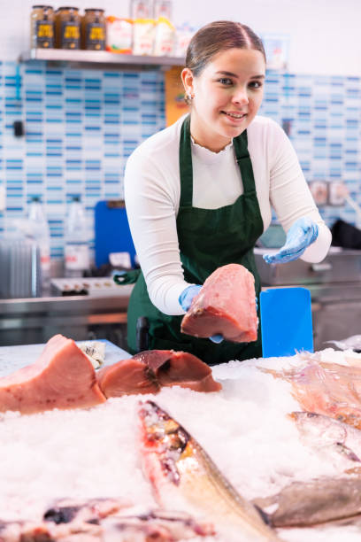 istock Responsive saleswoman demonstrating tuna in fish store 1464023096