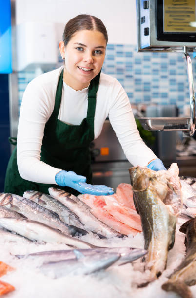 istock Positive saleswoman holding cod fish in fish store 1464023103
