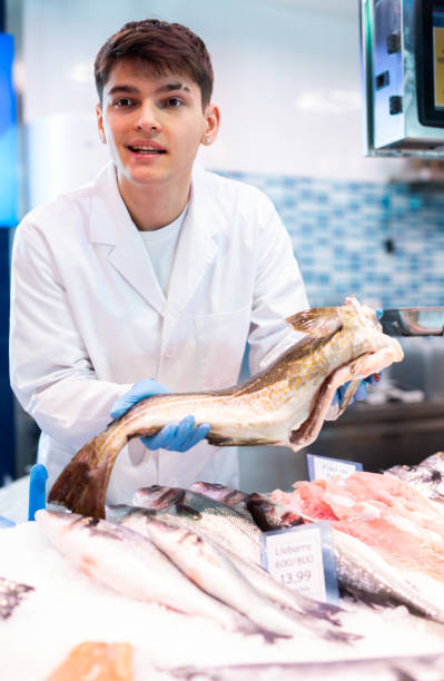 istock Positive salesman demonstrating cod in fish store 1464023226