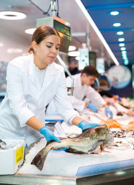 istock Positive saleswoman holding cod fish in fish store 1464023236