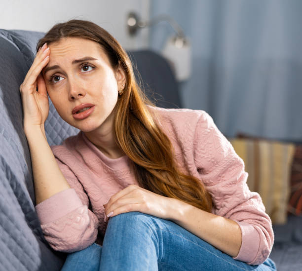 istock Upset woman crying while sitting on a sofa in room 1464025533