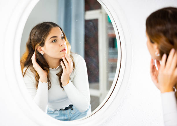 istock Young woman looking at herself in mirror 1464025620