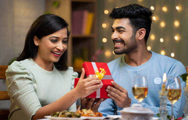 istock Young man giving Gift to girlfriend during candle light dinner at home - concept of relationship, romantic night and present 1464025679