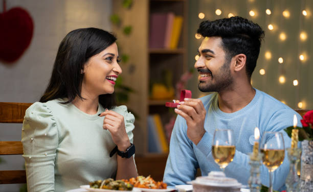 istock Happy young man proposing to girlfriend offering gold ring during anniversary celebration at home - concept of engagement, affection and relationship 1464025799
