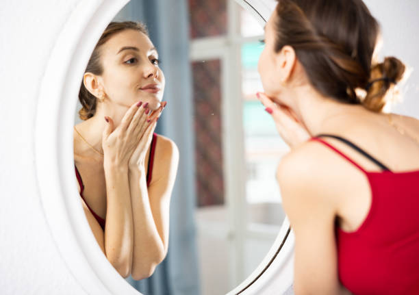 istock Young woman caring for her face while looking in mirror 1464025844