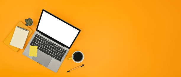 istock Horizontal image of laptop, notepad and sticky notes on yellow background. Copy space for text information or content. 1464031542