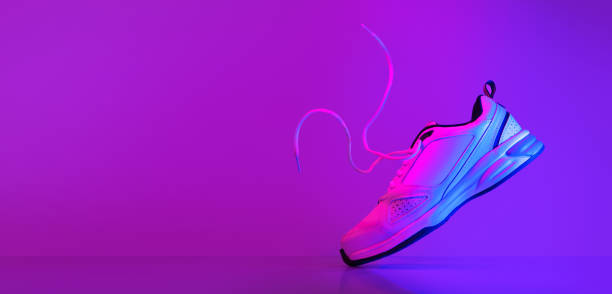istock White sneaker hovering in flight with hovering laces in neon lights. 1464034145