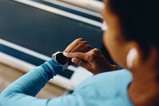 Close up of African American athletic woman using smart watch during sports training in a gym.