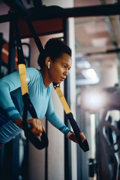 istock African American athletic woman using suspension straps while working out in gym. 1464035917