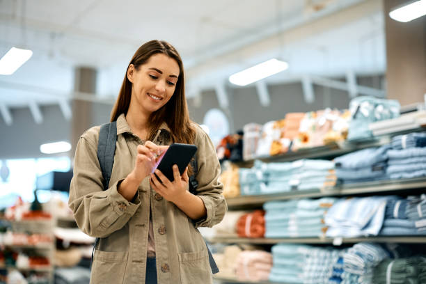 istock Young happy woman using mobile phone while shopping at the mall. 1464043588