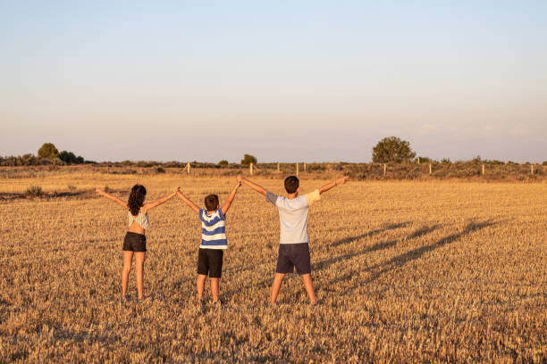 istock Three kids with open arms on a field at sunset 1464044453