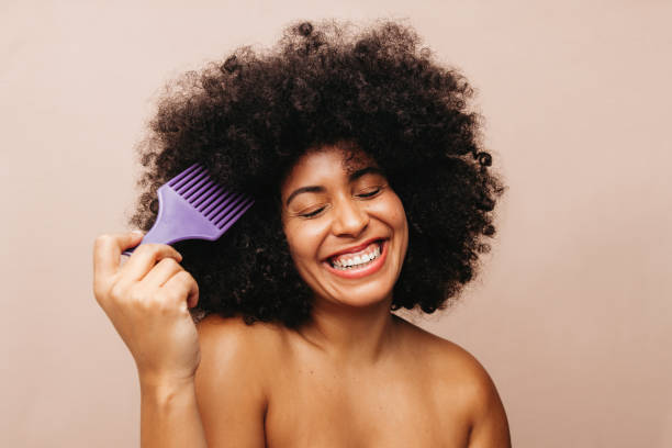 istock Beautiful woman of color combing her Afro hair in a studio 1464044607