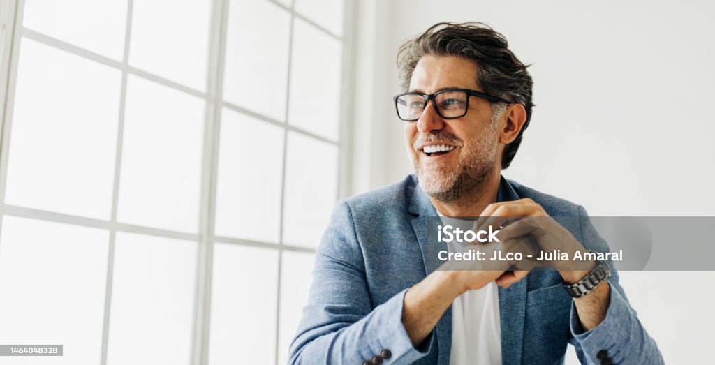 Homem de negócios olhando para fora da janela em um escritório - Foto de stock de Homens royalty-free Homem de negócios olhando para fora da janela em um escritório - Foto de stock de Homens royalty-free