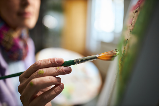 Close up of unrecognizable female painter painting in art studio.