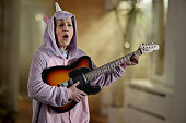 istock Senior woman signing while playing a guitar at home. 1464051216