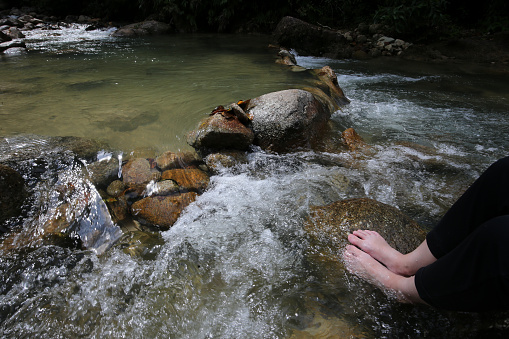 Human foot soaking in waterfall flowing water