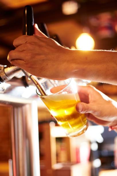 istock Vertical shot of a bartender dispensing beer into a glass at a pub 1464057147