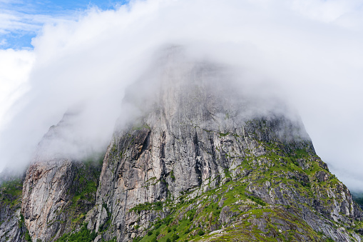 Mountain peak on Lofoten island covered in mist on a sunny day