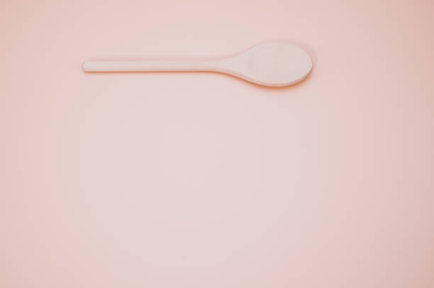 istock Wooden spoon isolated on a peach background with free space for text 1464058659