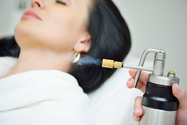 cosmetologist makes a cryomassage of the face to the patient – a cosmetological procedure of exposure to the skin with liquefied nitrogen using a cryodestructor apparatus stock photo