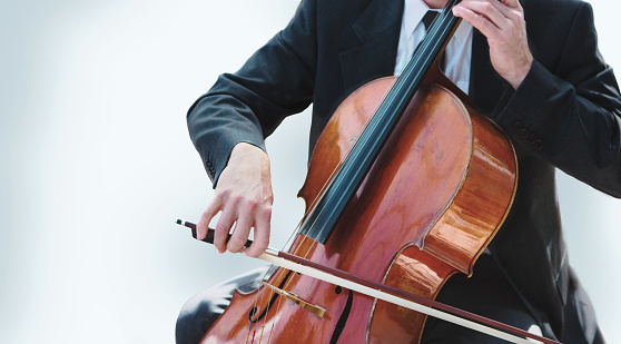 A man playing orchestra cello on white background