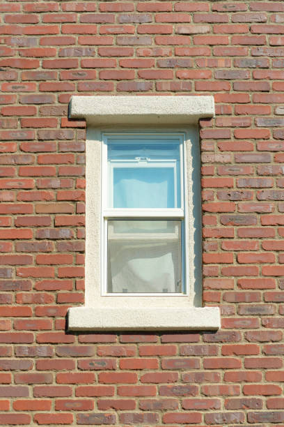 istock Vertical shot of a brick-walled and a glass window in a building 1464064565