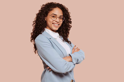 Young smiling woman entrepreneur with crossed arms at studio