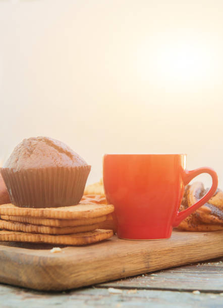 Empty space red coffee cup template with chocolate muffin in outdoor city cafe, sunny morning breakfast