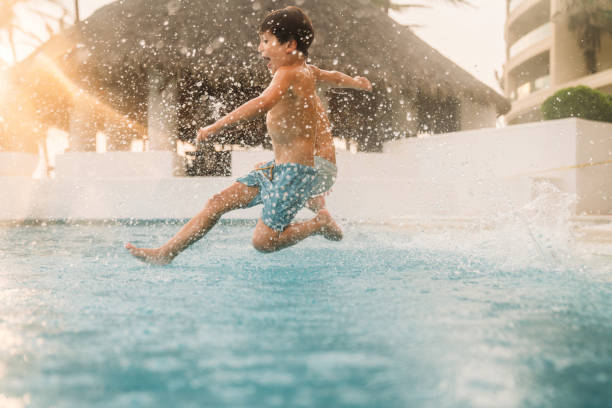 Boys jumping into the pool stock photo