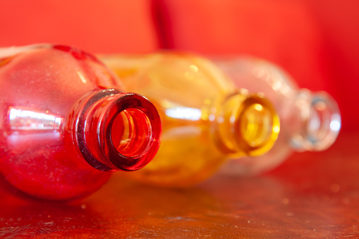 A closeup shot of three colorful glass bottles on a red background