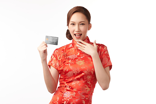 Happy Chinese new year, Beautiful young Asian woman wearing traditional cheongsam qipao dress holding credit card on white background,
