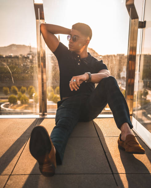 istock Handsome Hispanic guy in sunglasses sitting on a balcony floor and posing 1464075213